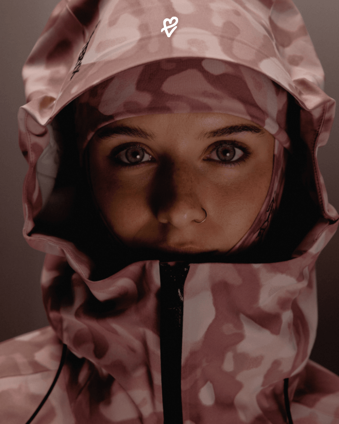 Arc'teryx x Atomic iş birliğiyle hazırlanan Grottoflage desenli 2025 kış koleksiyonundan bir görünüm: teknik mont ve kayak ekipmanlarıyla şehirli bir silüet