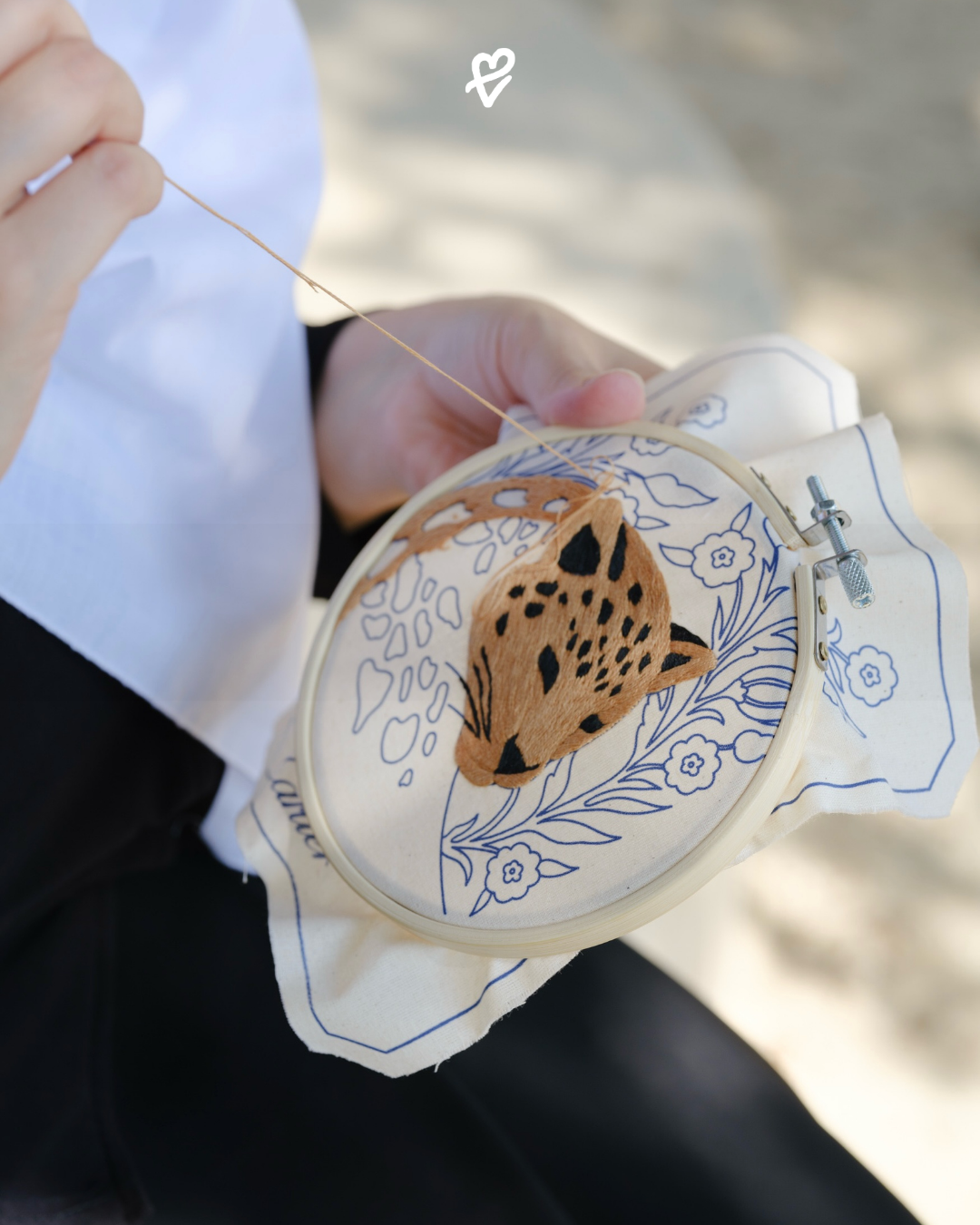 Cartier × Salim Azzam nakış kitinde çiçekli çizimler arasındaki panter başı, iplikler ve dikiş yönergeleri.