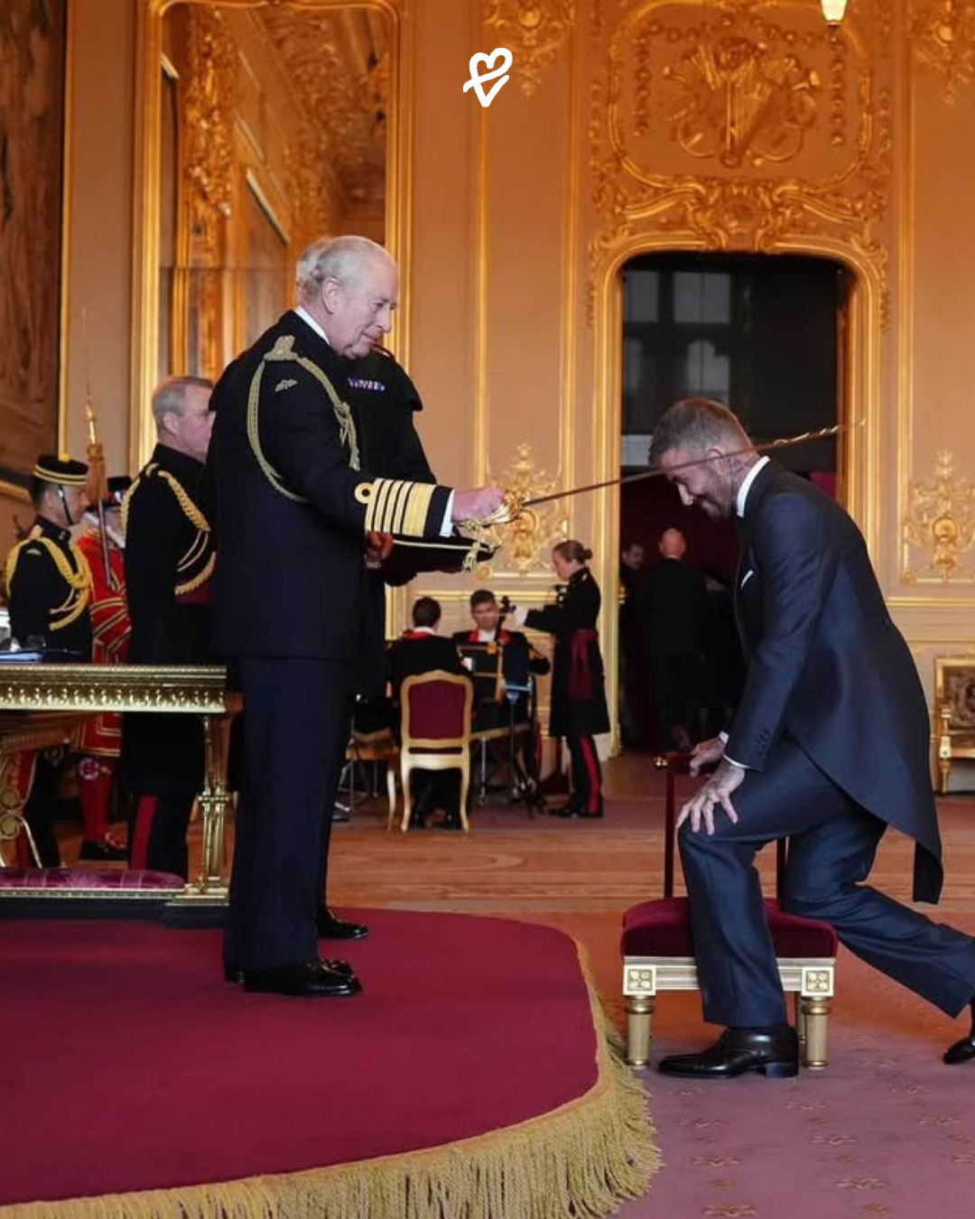 David Beckham, şövalyelik unvanı töreninde koyu renkli üç parçalı takımıyla ve yanında Victoria Beckham ile birlikte Buckingham Sarayı'nda.