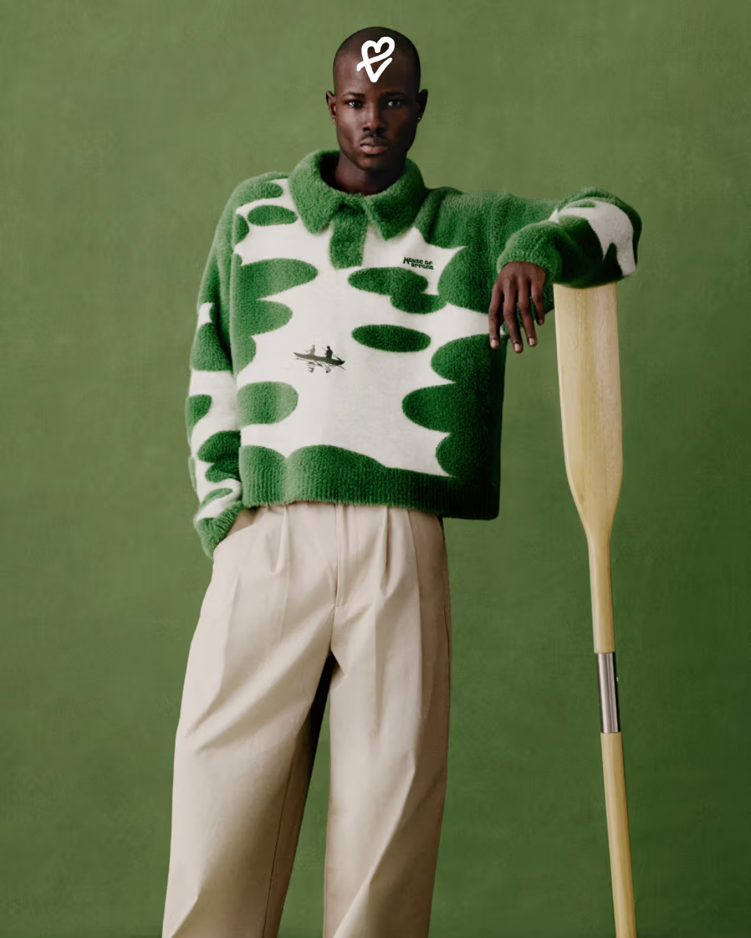 House of Errors AGUIRRE koleksiyonundan shaggy örgü kapüşonlu kazak giyen bir model, yeşil bir doğa manzarasında poz veriyor.