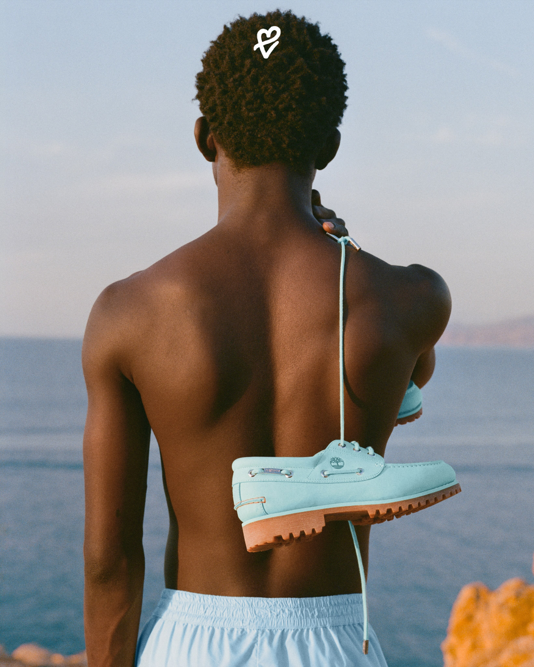 Jacquemus x Timberland iş birliğine ait, lagün mavisi renginde premium deriden üretilmiş, metal charm detaylı ve ton-sür-ton logolu üç delikli boat shoe ayakkabı tasarımı.