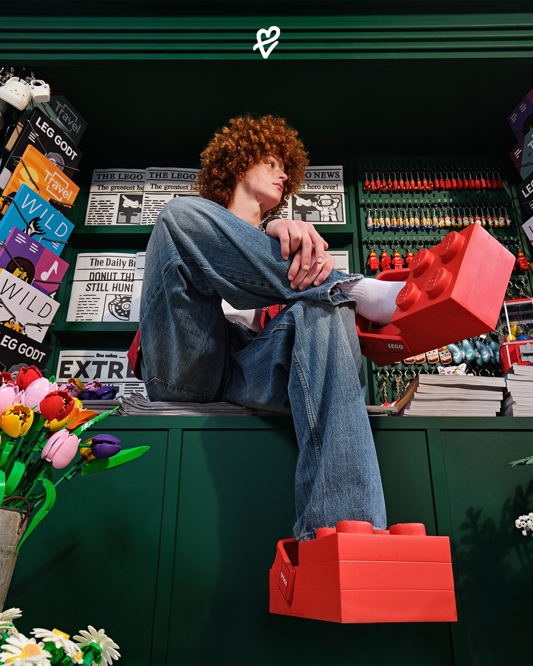 Parlak kırmızı LEGO x Crocs Brick Clog ayakkabısı ve yanında minyatür LEGO figürü