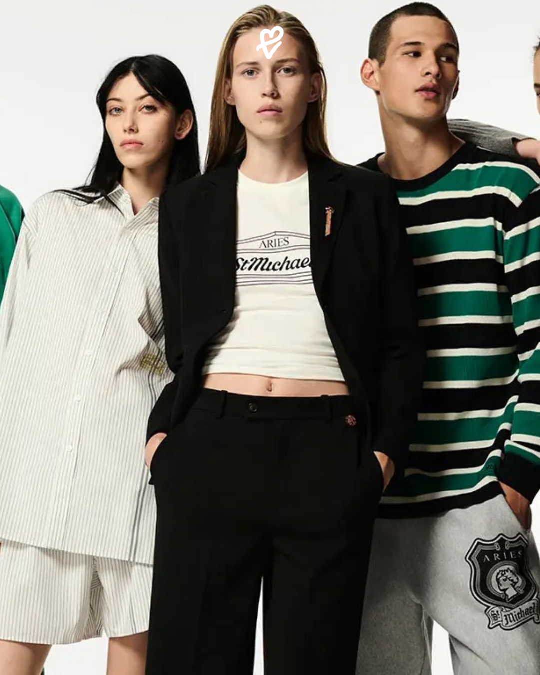 M&S x Aries koleksiyonunda yer alan, yeniden yorumlanmış St Michael logosu taşıyan pembe sweatshirt ve çizgili terzilik parçaları.