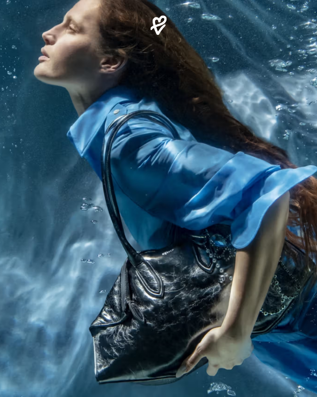 Suyun altında poz veren modelin omzunda McQueen Manta çanta, ışık kırılmasıyla birlikte dramatik bir etki yaratıyor