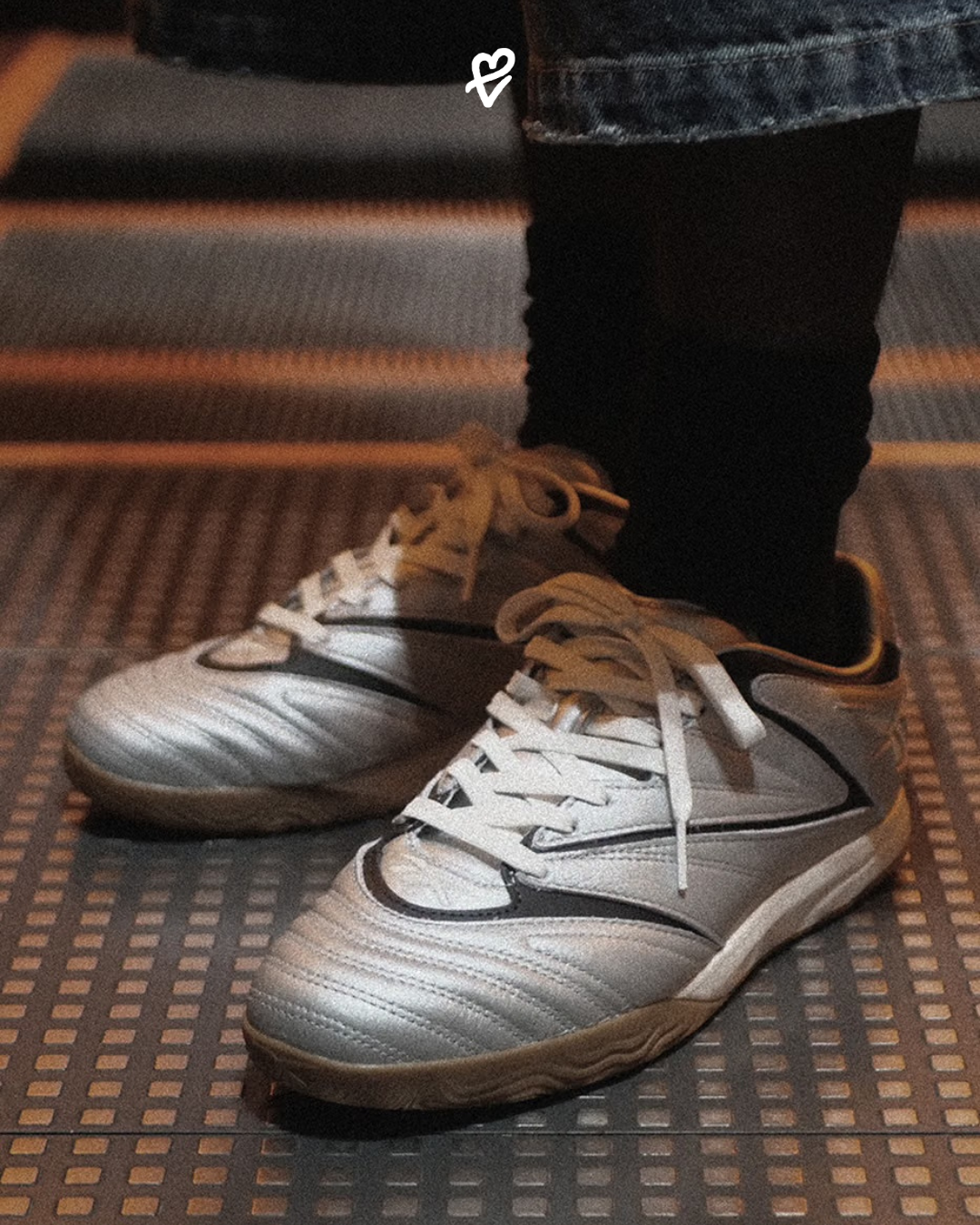 Metalik gümüş tam tahıllı deri kaplamaya, siyah köşeli dikiş hatlarına ve gum kauçuk tabana sahip Reebok Sidewinder 96 ID spor ayakkabı tasarımı.