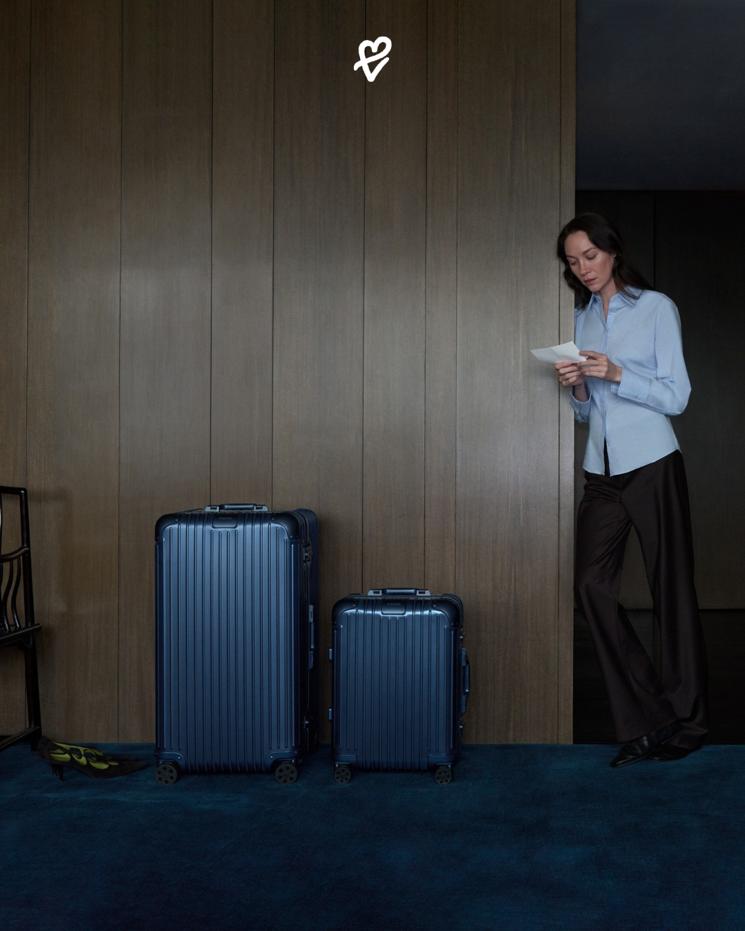 Sinematik gece ışığında sergilenen, anodize alüminyum yüzeyli ve groove çizgilerine sahip yeni derin gece mavisi RIMOWA Ink Blue Cabin bavul tasarımı.