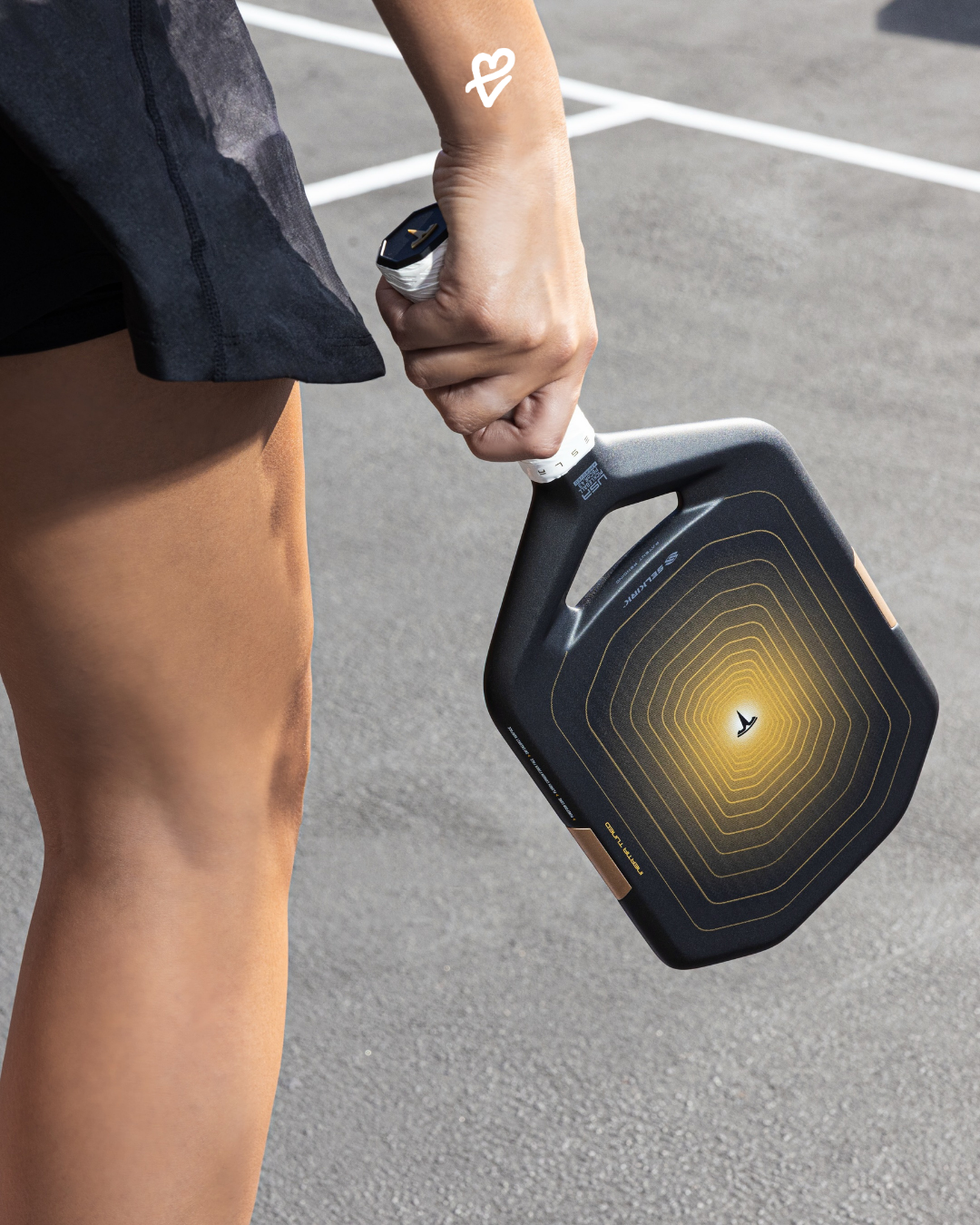 Tesla Cybercab modelinin altın tonlarını taşıyan, Florek karbon fiber yüzeye ve aerodinamik hatta sahip Selkirk Aurum pickleball raketi.