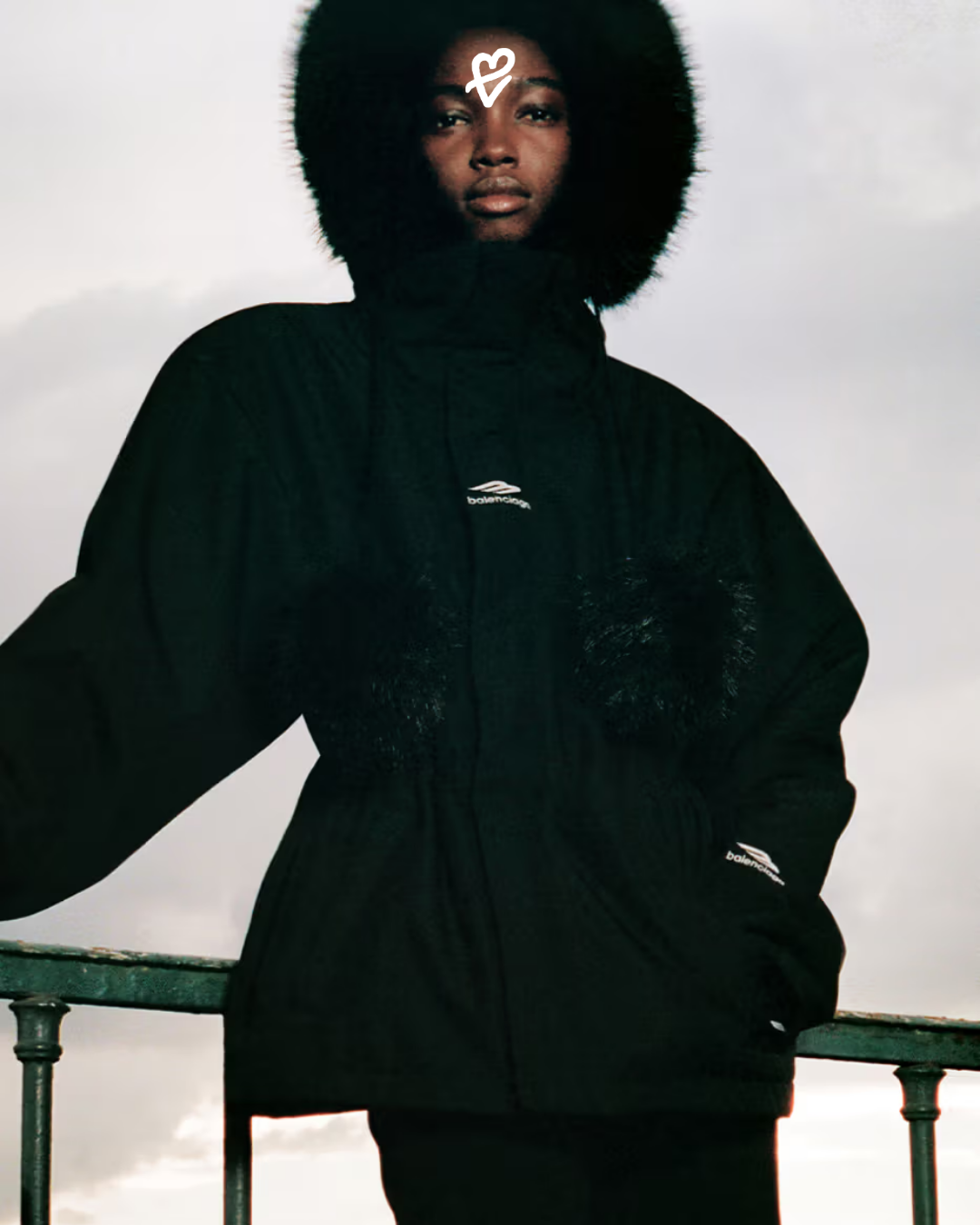 Balenciaga 2025 Kayak Koleksiyonu'ndan oversized ve katmanlı dış giyim parçalarıyla karla kaplı dağ manzarasında bir model.