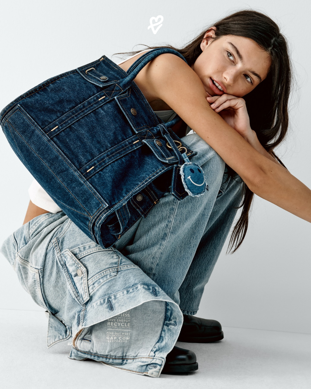 GapBag kampanyasında denim Five-Pocket Tote çantasını taşıyan siyah deri ceketli model.