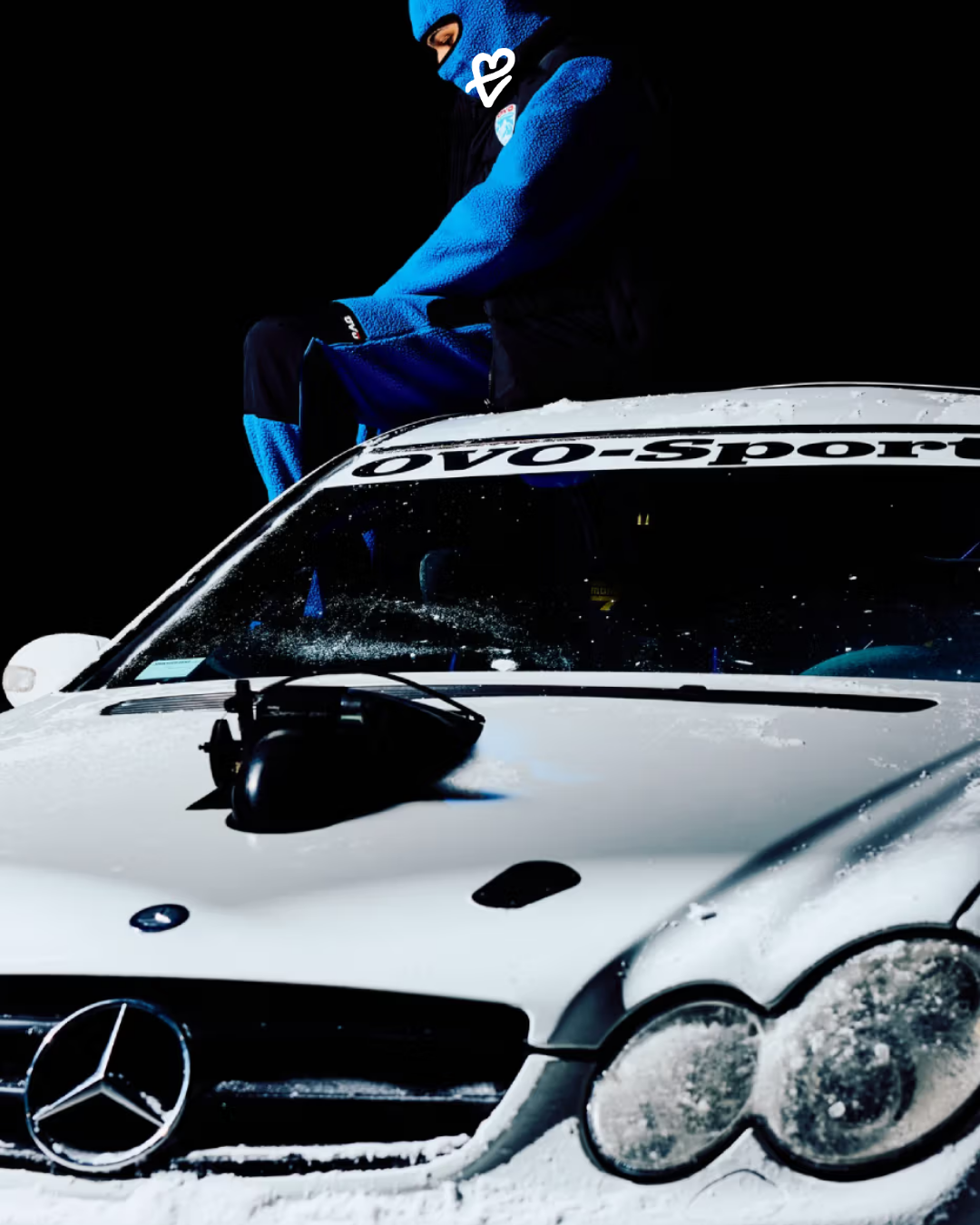 OVO Winter Survival 2026 koleksiyonundan siyah termal mont giymiş bir model, şehir fonunda yürürken